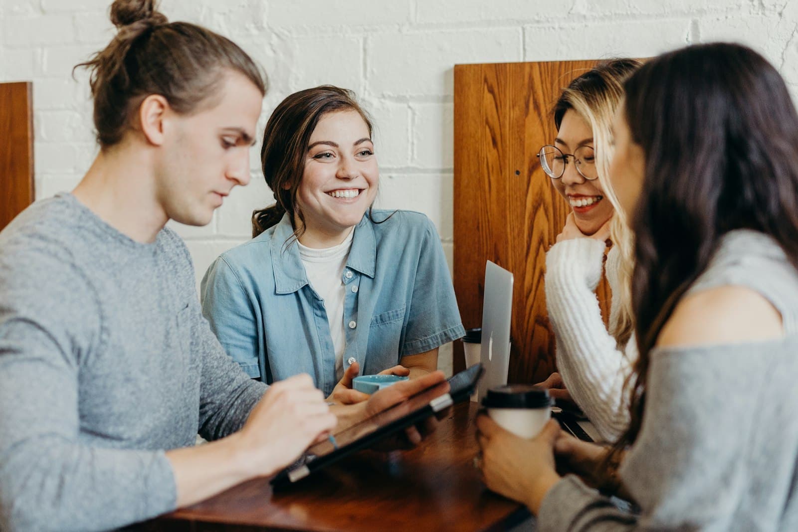 Four young people working together around a table, smiling
